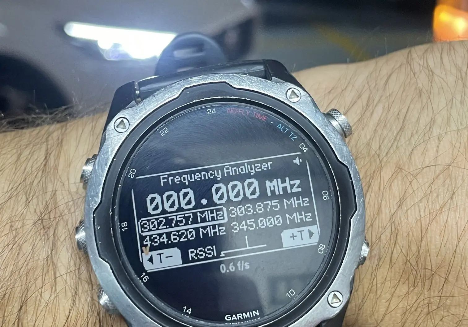 Sub-GHz Frequency Analyzer visible on the watch in an underground car park, the Flipper in a pocket